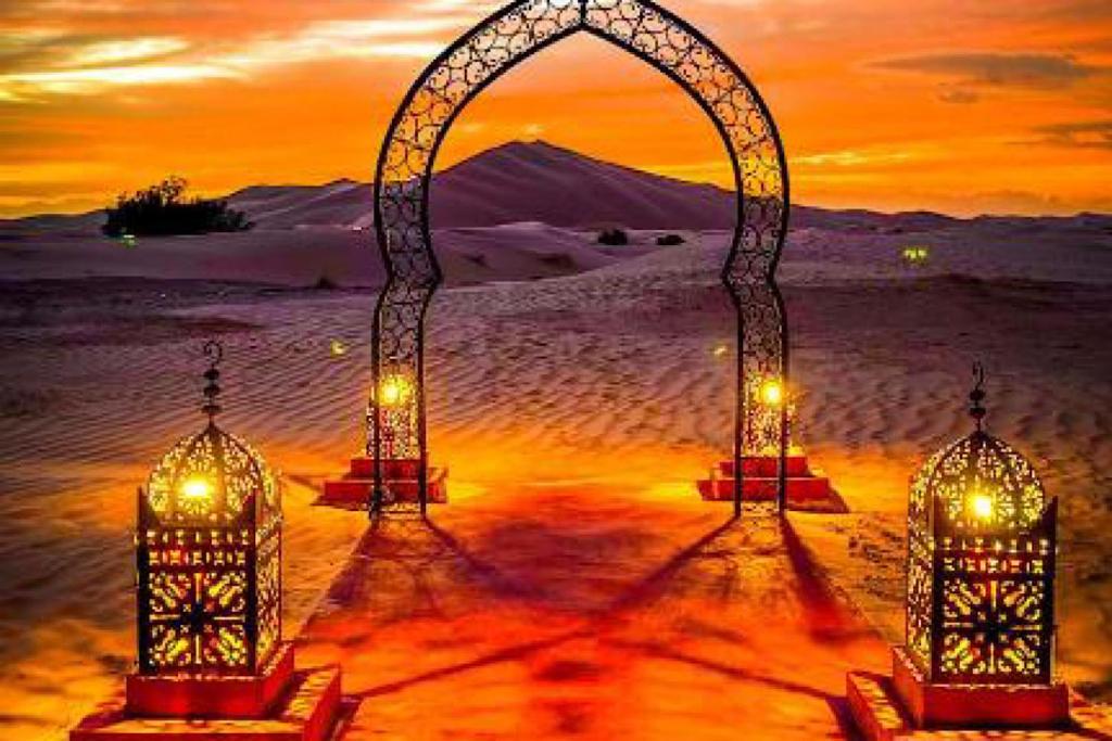 two lights under an arch in the desert at sunset at Merzouga Best Luxury Camp in Merzouga
