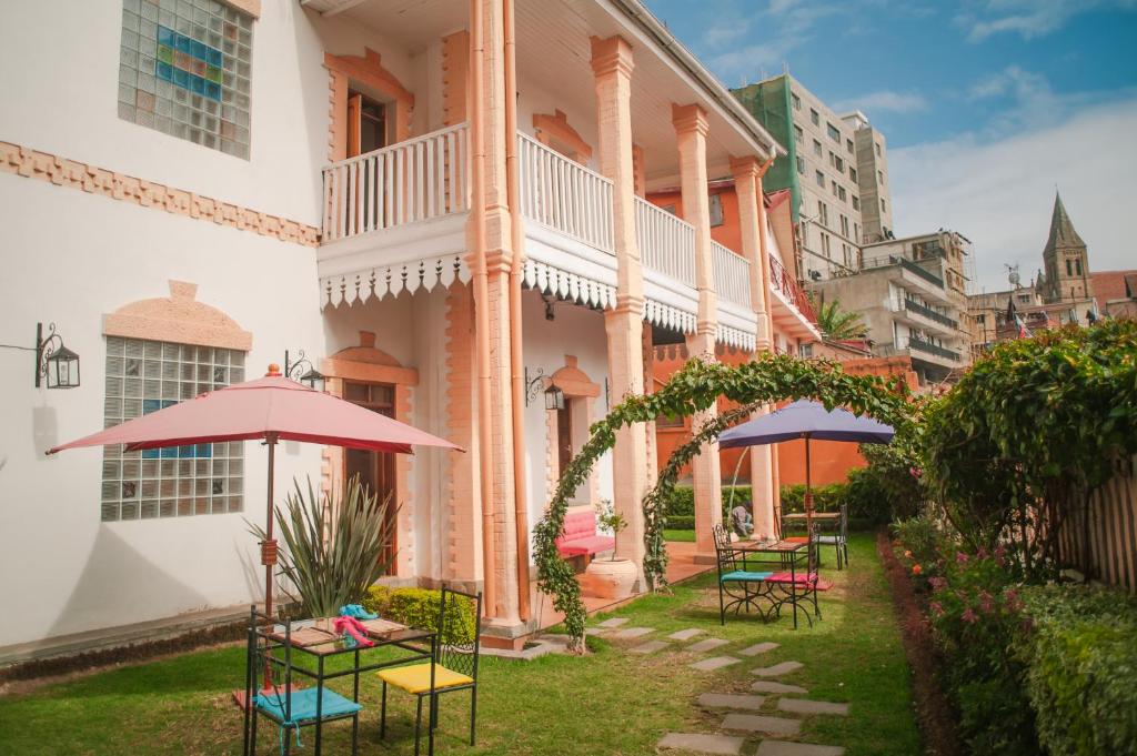 a patio with tables and umbrellas in front of a building at Maison Lovasoa in Antananarivo