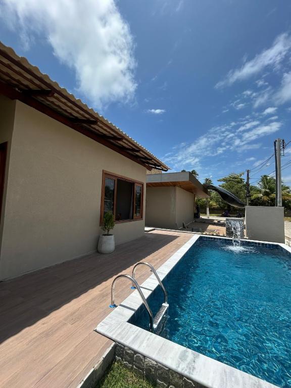 a swimming pool in front of a house at Casamares Ipioca Beach Hibiscus Maceió in Maceió