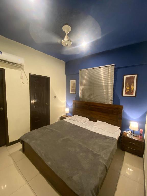 ein Schlafzimmer mit einem großen Bett mit blauen Wänden in der Unterkunft Beach Side Studio Apartment in Karatschi