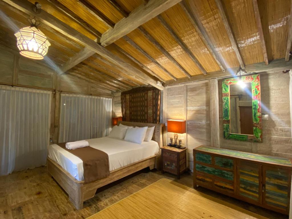 ein Schlafzimmer mit einem Bett, einem Tisch und einem Spiegel in der Unterkunft Secret Wooden Cabin - Lylium Cabin Suite in Jimbaran