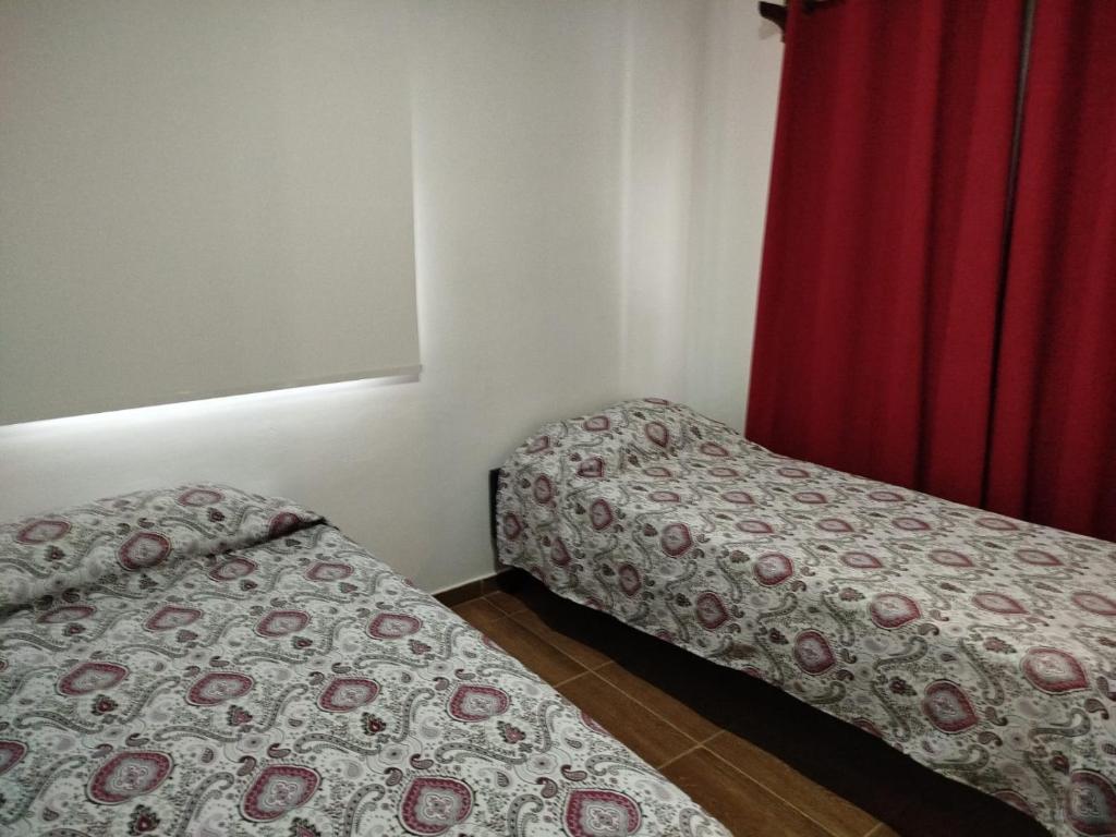 a bedroom with two beds and a red curtain at Edificio Rey Niño in Posadas