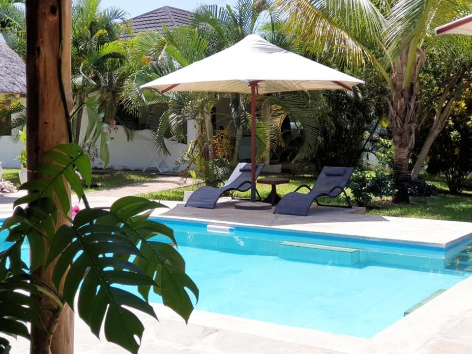 einen Pool mit 2 Stühlen und einem Sonnenschirm in der Unterkunft Diani Gardens Cottage in Ukunda Airport