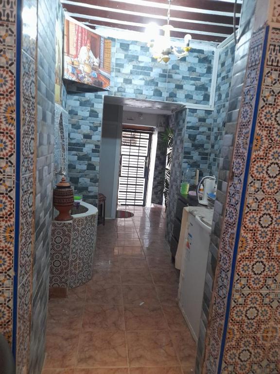 une cuisine avec des murs en carrelage bleu et un couloir dans l'établissement Dar Elkorchi, à Fès