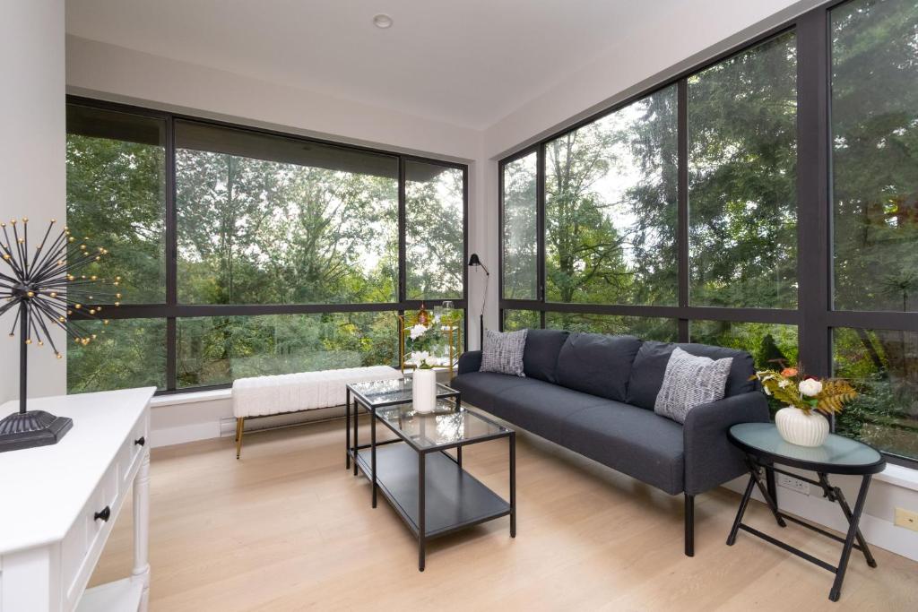 Una sala de estar con un sofá y grandes ventanales. en Stylish Scenic Oasis 2-Bedroom Suite West Van, en West Vancouver