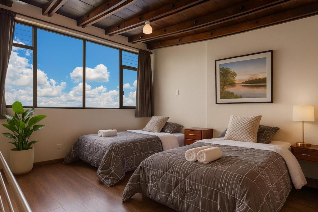 twee bedden in een kamer met grote ramen bij Panoramic Loft Unique Windows and Views in Cuenca