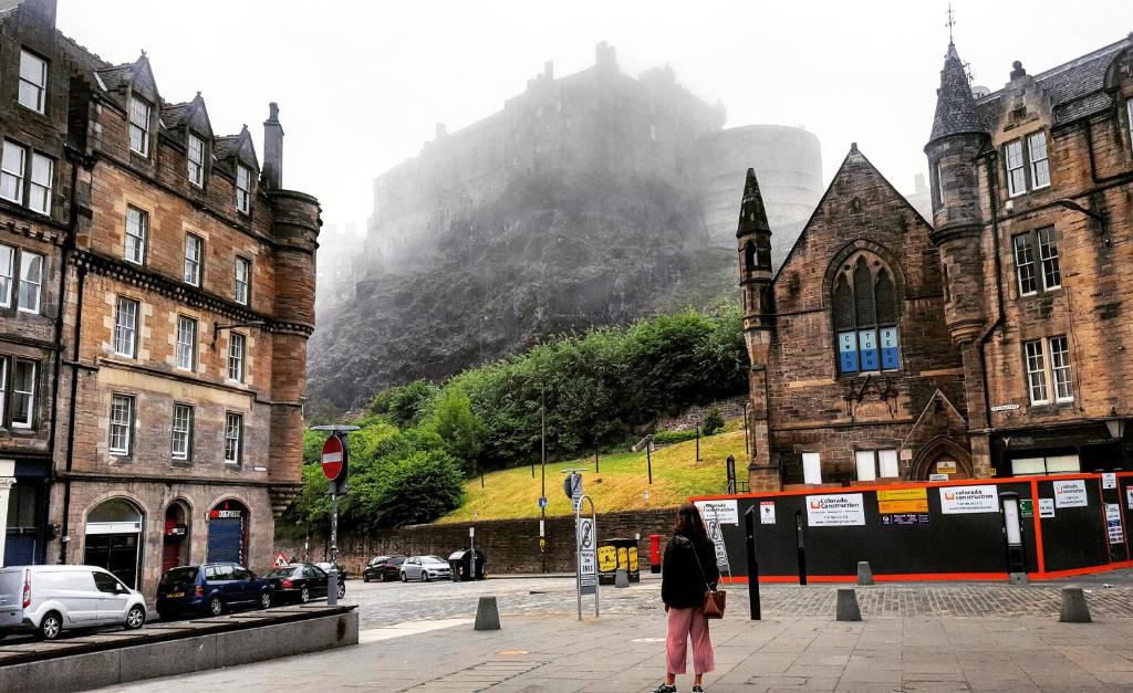 une femme debout dans une rue devant les bâtiments dans l'établissement Three Bedrooms Flat in Central Edinburgh Old Town , Grassmarket Heart of Edinburgh Flat Sleeps 6 , EH1 58 Grassmarket, Edinburgh, à Édimbourg