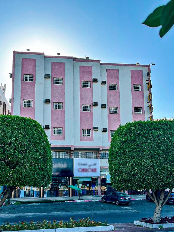 a pink and white building with a car in a parking lot at أللورا زون - Alora Zone in Abha