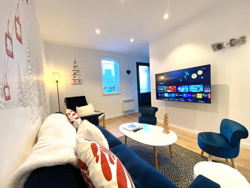 ein Wohnzimmer mit einem blauen Sofa und einem Fernseher in der Unterkunft CHALET LAC BLEU Luchon proche Thermes 3ch terrasse bbq pkg 7p in Saint-Mamet