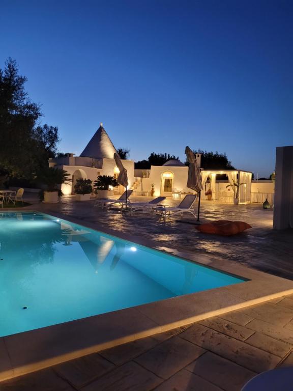 ein Schwimmbad in der Nacht mit einem Haus im Hintergrund in der Unterkunft Trullo il Gelso with Private Salt Water Infinity Pool and Jacuzzi inside in San Michele Salentino