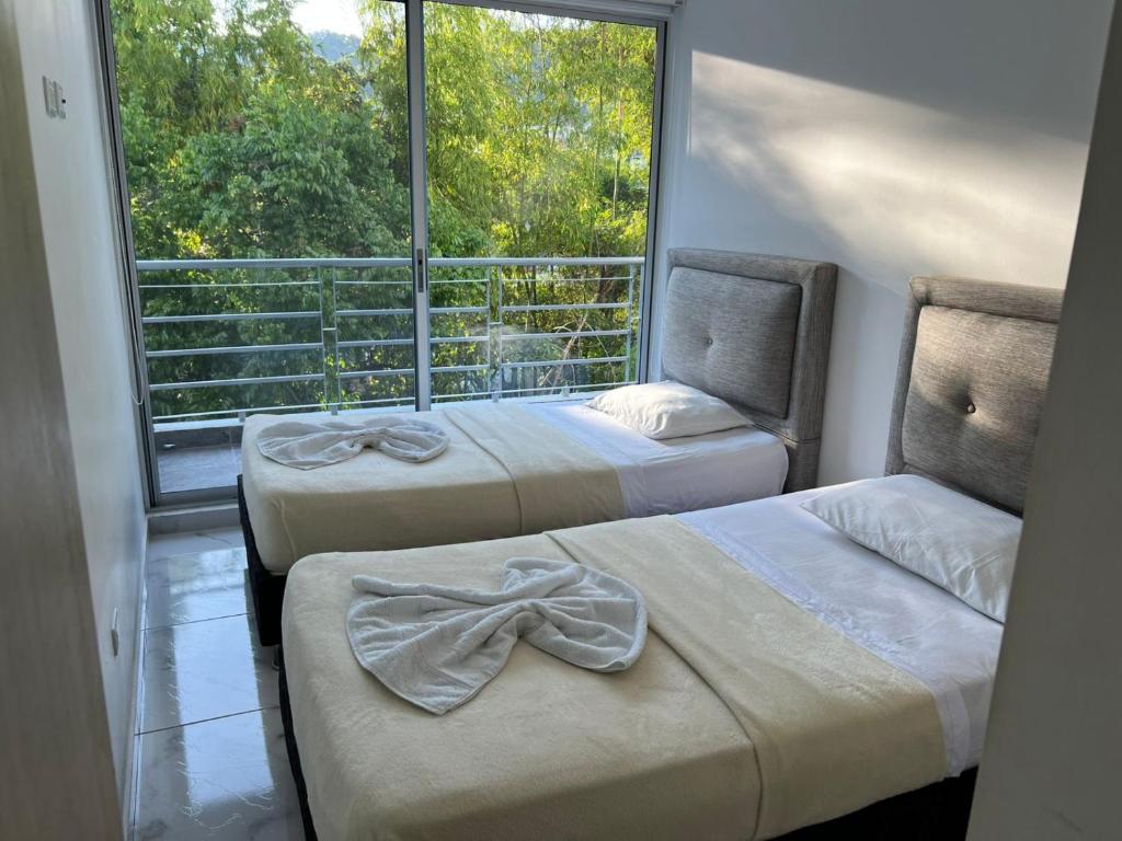 twee bedden in een kamer met een groot raam bij centrico Apartamento con piscina Anapoima in Anapoima