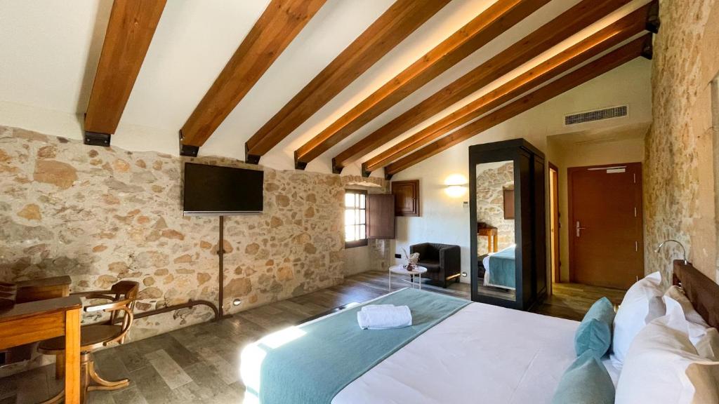 a bedroom with a large bed with a tv on the wall at Hotel Molí de l'Escala in L'Escala