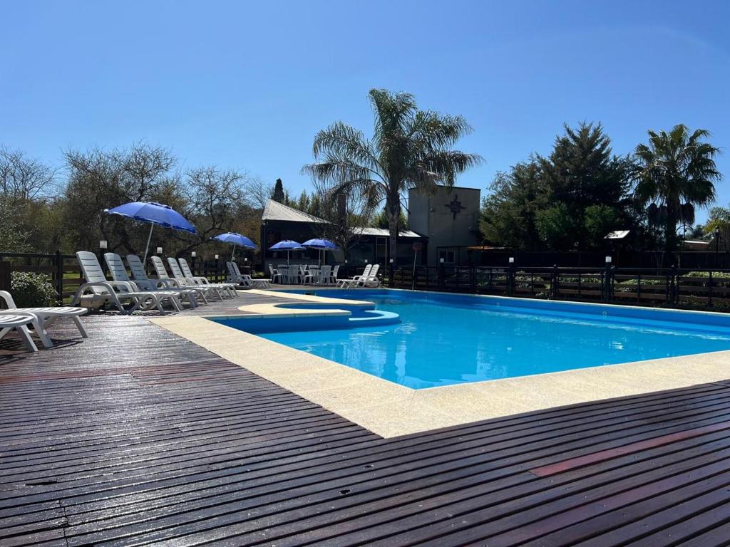 a swimming pool with chairs and umbrellas on a deck at Tribales del Este in Gualeguaychú