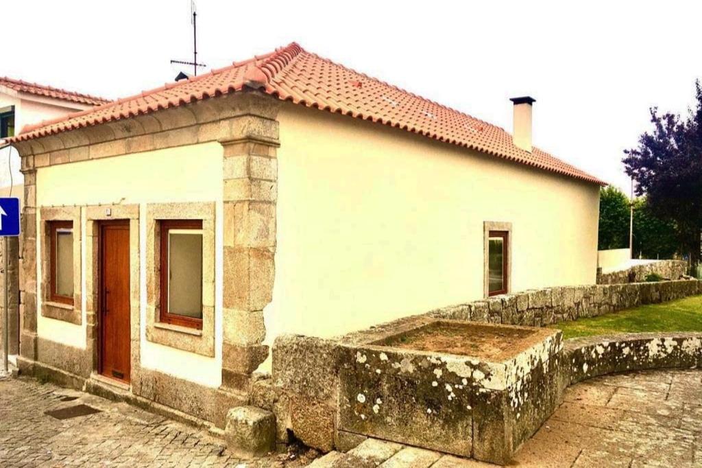 a small white house with a stone wall next to it at Azurara Martins House in Azurara