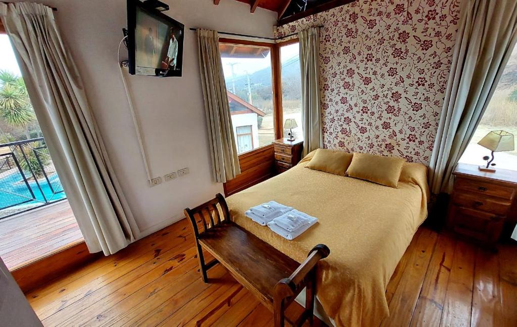 a bedroom with a bed and a table and a window at Cabañas Ayres del Lago in Potrero de los Funes