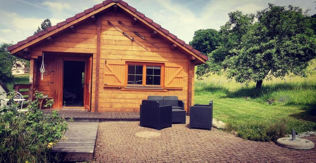 a small wooden cabin with two chairs in front of it at Chalet L' Aventurière in Masevaux