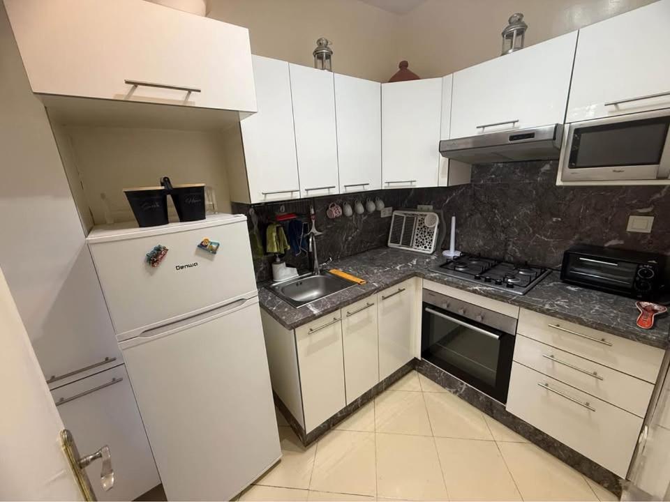 une cuisine avec des armoires blanches et un réfrigérateur blanc dans l'établissement Résidence Al madmounae agadir, à Dcheïra