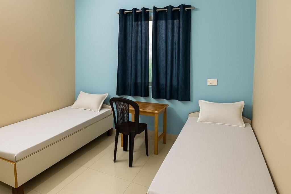 ブッダガヤにあるDev Residencyのベッド2台と椅子とテーブルのある部屋
