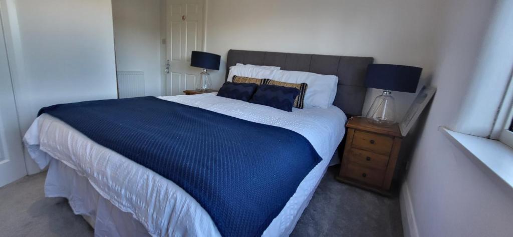 a bedroom with a large bed with blue sheets and pillows at The Willows in Stockton-on-Tees