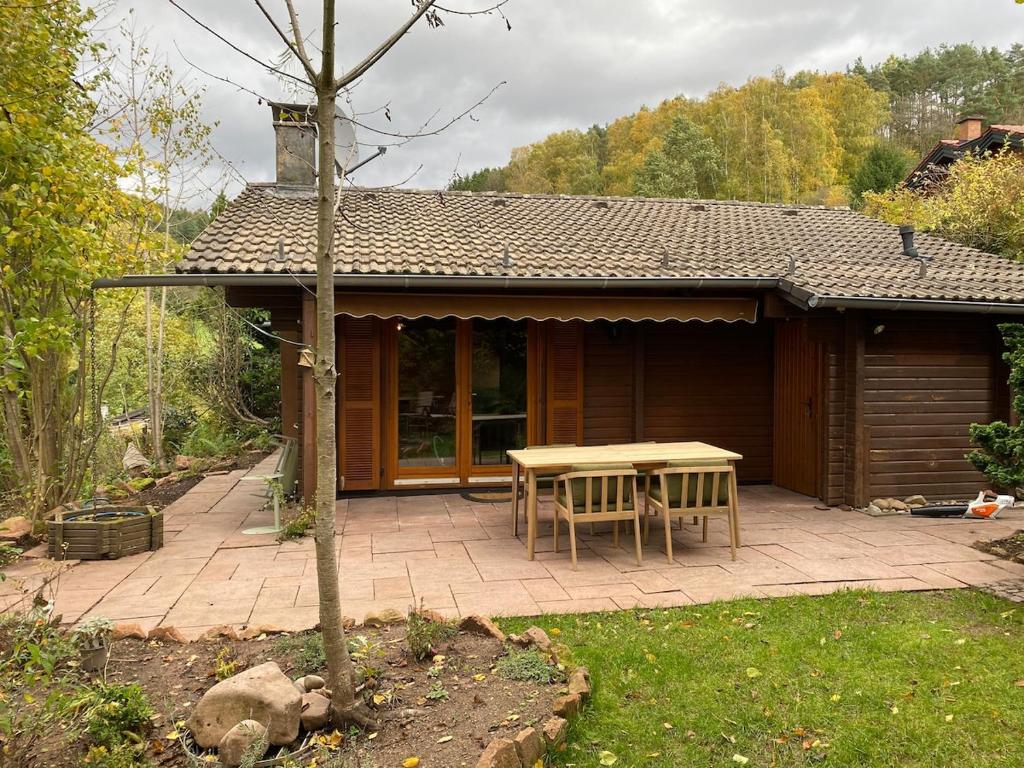 a patio with a table and chairs in front of a cabin at Ruhige Hütte mit toller Aussicht in Dammbach