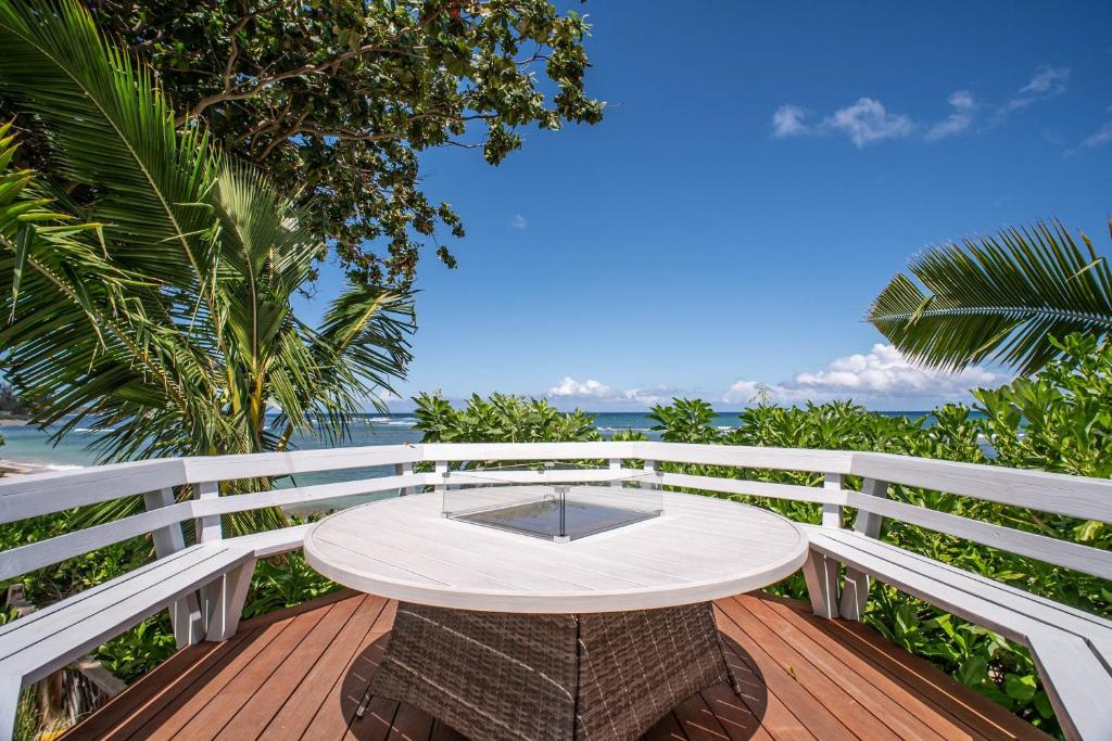 a table on a deck with the ocean in the background at The Emerald House II apts in Waialua
