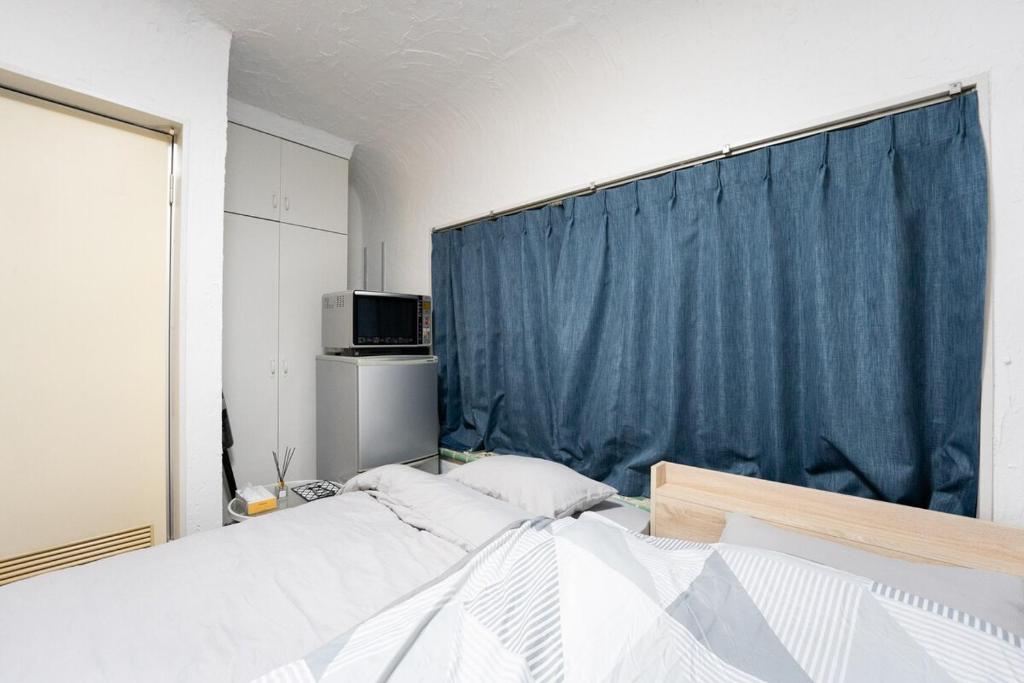 a bedroom with two beds and a blue curtain at 御嶽ハウス in Tokyo
