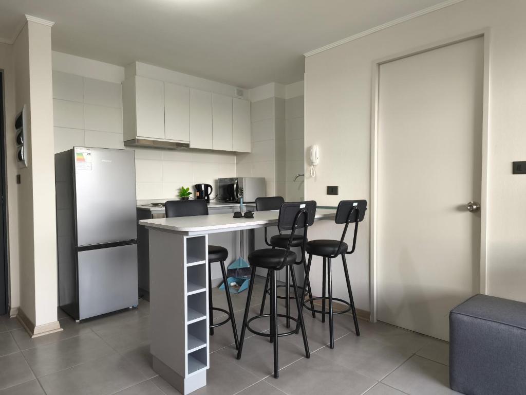 a kitchen with a counter with stools and a refrigerator at Departamento amoblado in San Pedro de la Paz