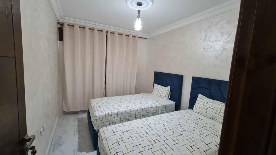 a bedroom with two beds and a window at Résidence al BASSLAM agadir in Agadir