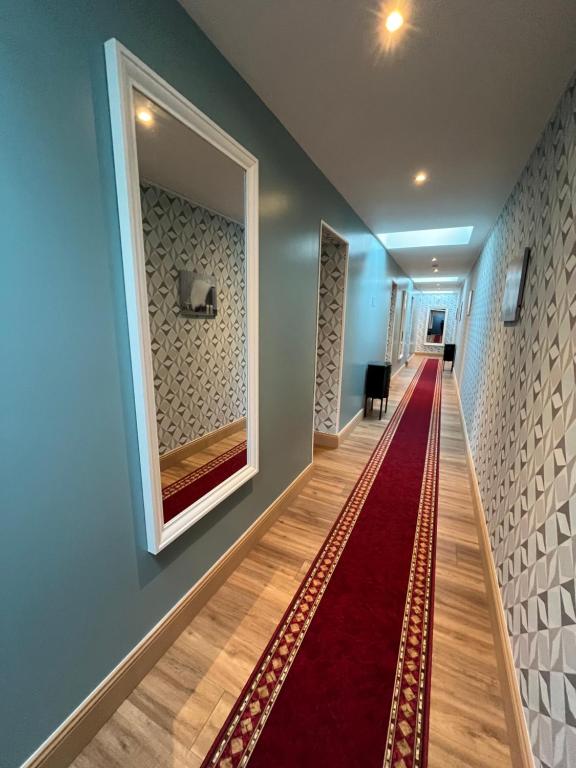 a hallway with a red carpet and a mirror at Hôtel Déco'lia-Soirée étape in Ballon