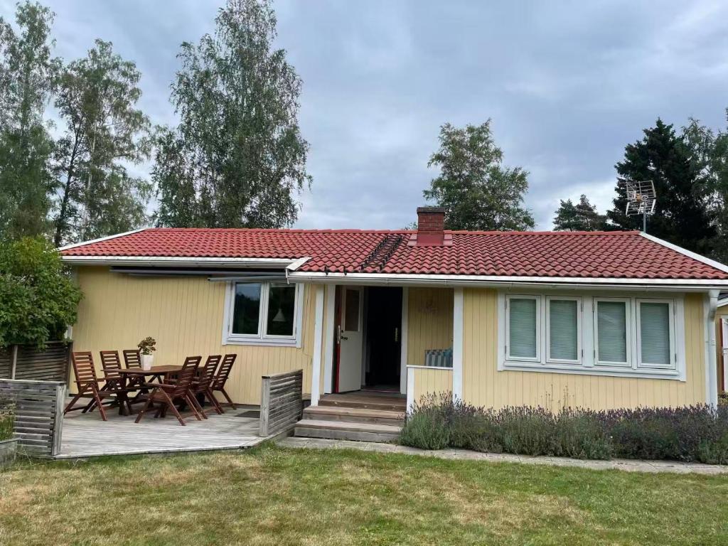 a yellow house with a table and chairs at Charmig Villa bredvid sjön Örlen in Tibro