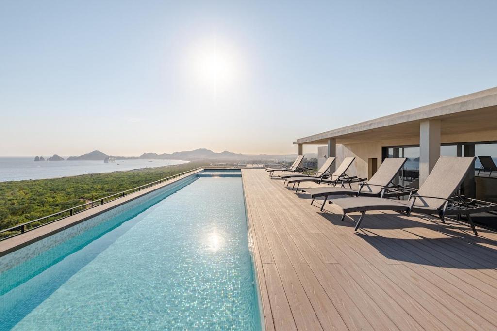 a row of chairs sitting on a deck next to a swimming pool at Luxury apartment overlooking the Arch in Cabo San Lucas