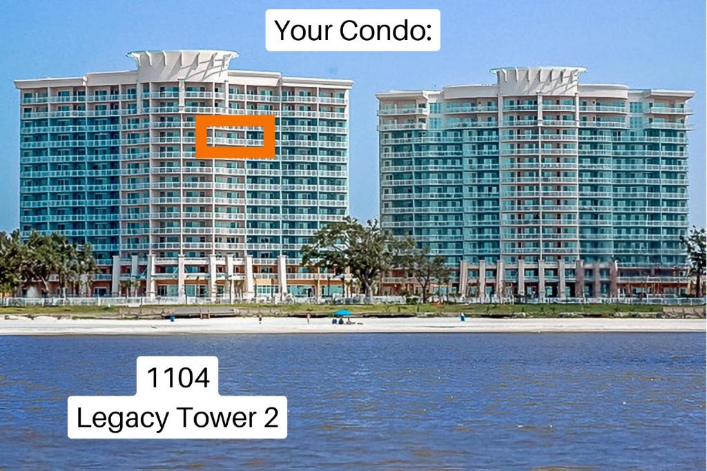Ein großes Gebäude mit einem orangefarbenen Schild daran, neben dem Wasser in der Unterkunft Beachview Condo at Legacy Tower 2 -1104 - fully furnished 2 bedroom 2 bath in De Buys