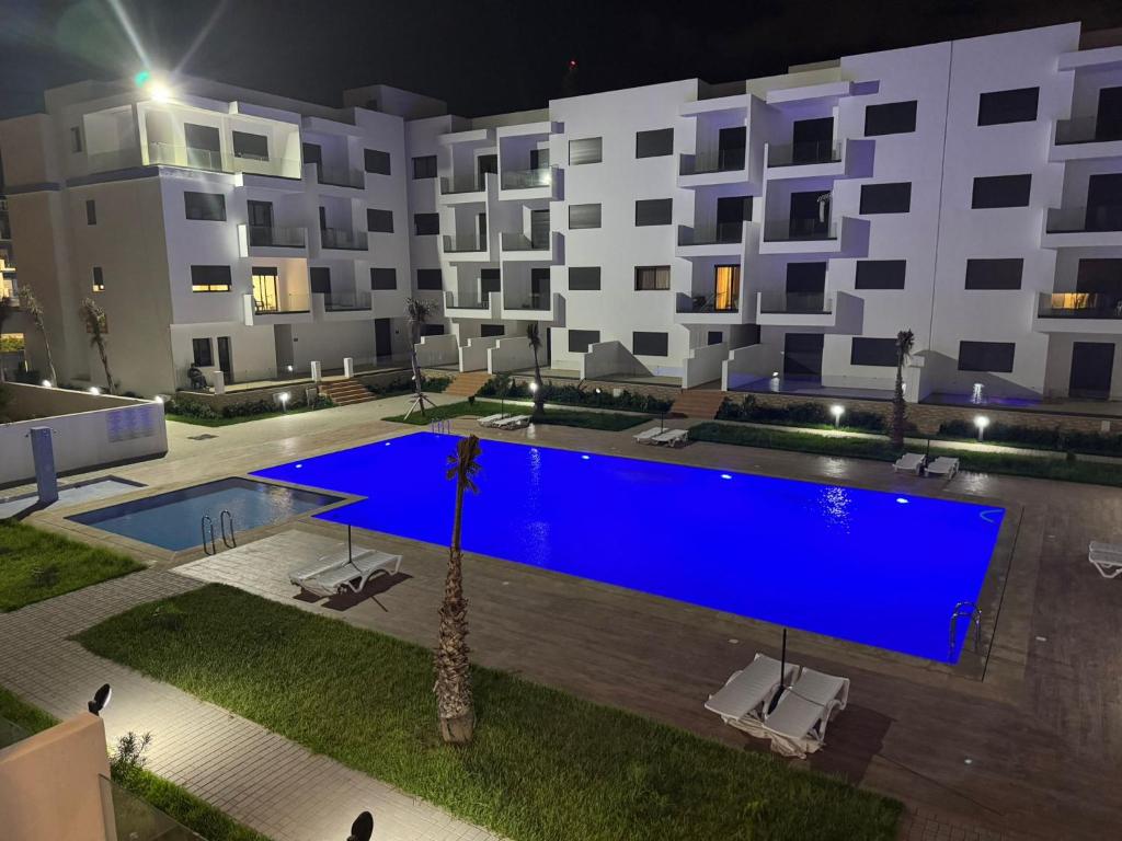 a large blue swimming pool in front of a building at Residence Rmilat Garden Martil in Martil