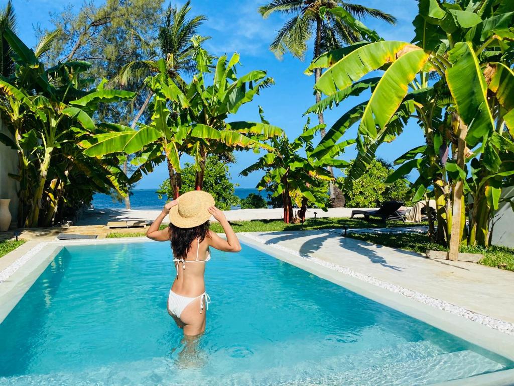 une femme en bikini et chapeau dans une piscine dans l'établissement Luxury LIONS VILLAS ZANZIBAR - with Private Cook&Infinity Pools, à Kiwengwa