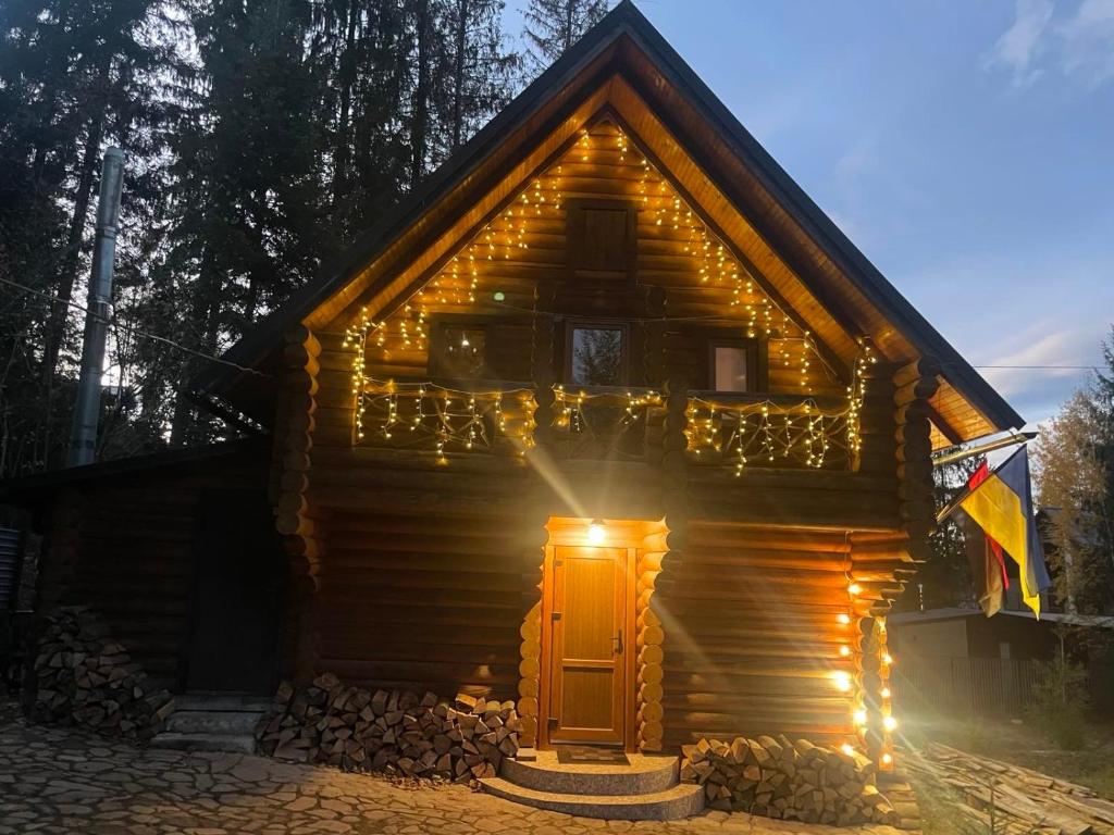a wooden house with lights around the door at Мʼята in Mykulychyn