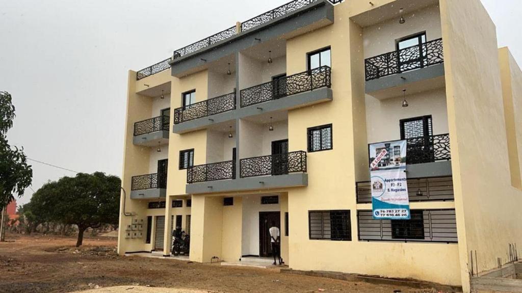 a man standing in front of a building at Immeuble Sali Laye in Darou Rhamane