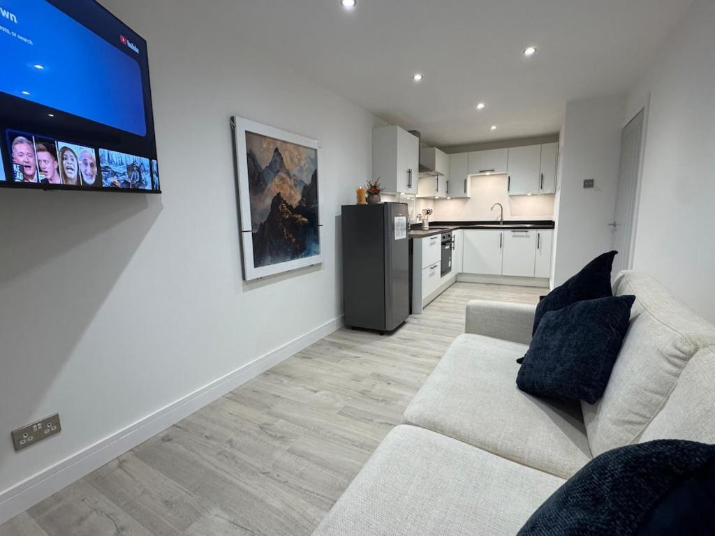 a living room with a couch and a tv on a wall at Cosy Modern 2 Beds Chorley Center in Chorley