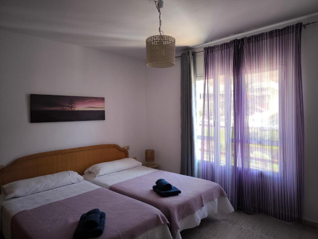 ein Schlafzimmer mit zwei Betten und einem großen Fenster in der Unterkunft Acogedoras Habitaciones Privadas zona Costera Wifi in Morro del Jable