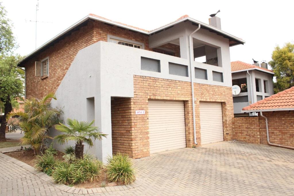 een stenen huis met twee garagedeuren op een oprit bij Nested at L&MX in Centurion