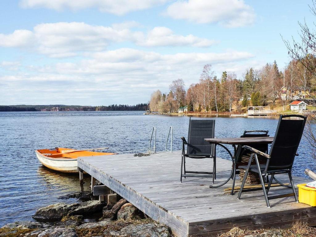 OrmarydにあるCharming Cottage by Sjunnaryd Lakeの椅子とテーブルとボートのある木製の桟橋