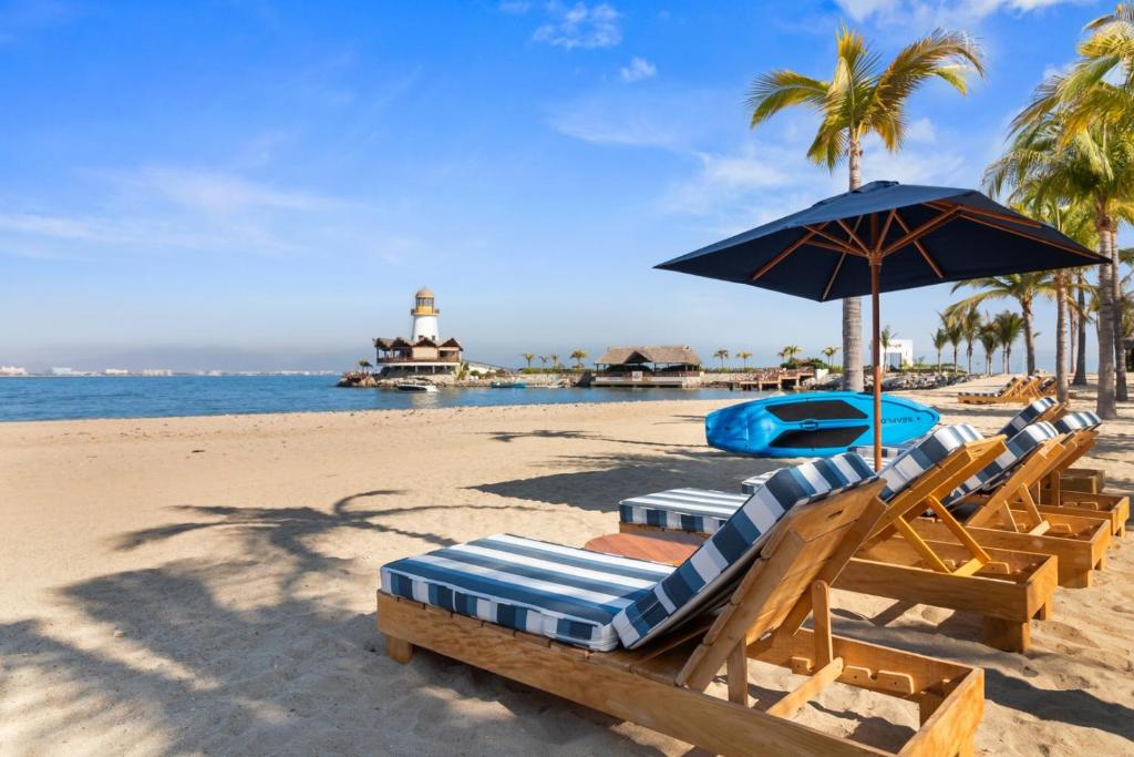 a group of lounge chairs and an umbrella on a beach at Peaceful Retreat with Pool – Ideal for Relaxation in Cruz de Huanacaxtle