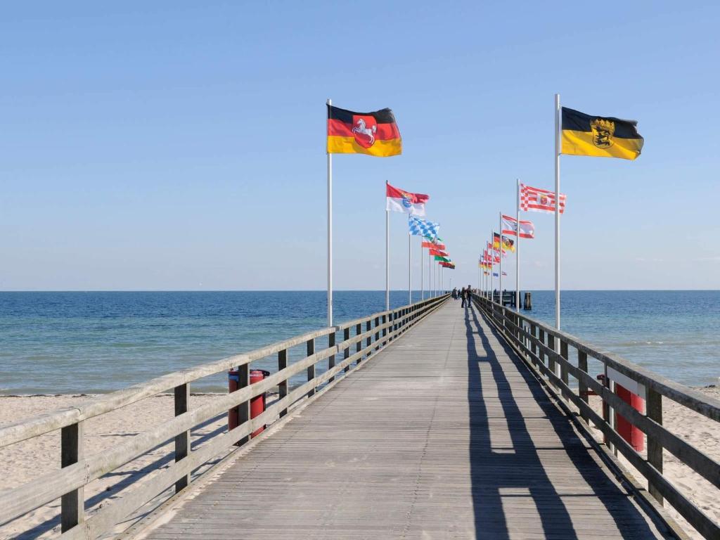 a wooden pier with flags on the beach at 6 person holiday home in Großenbrode in Großenbrode