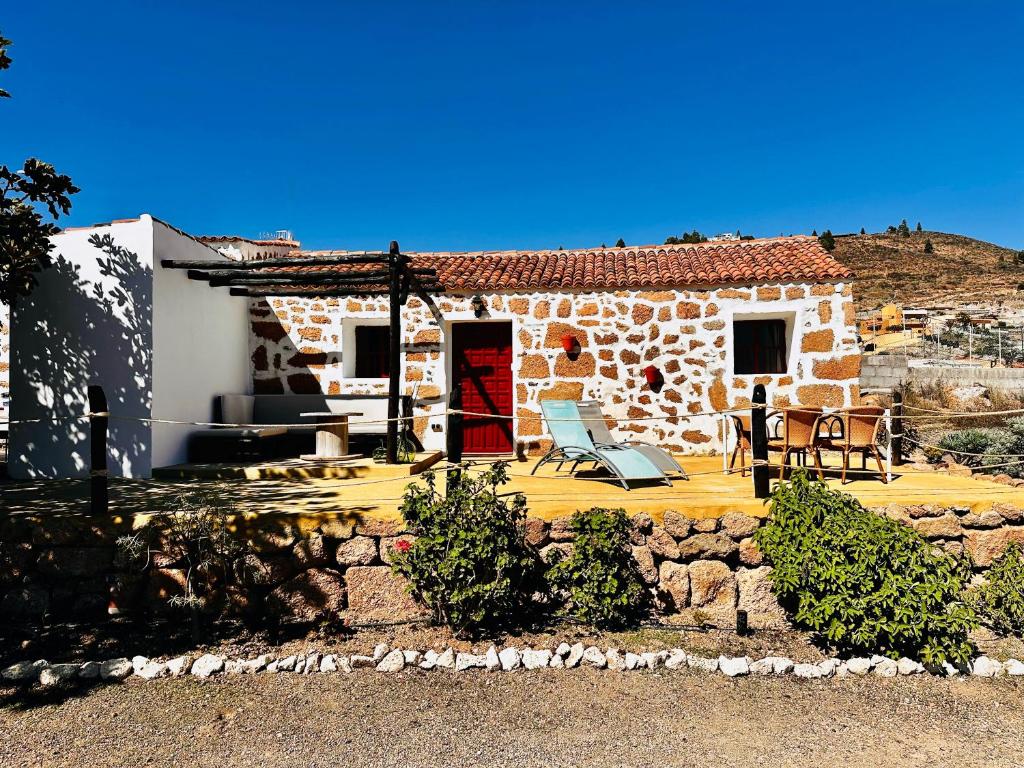 una casa de piedra con una puerta roja y un patio en Las Casitas - Casa Higo, en Granadilla de Abona