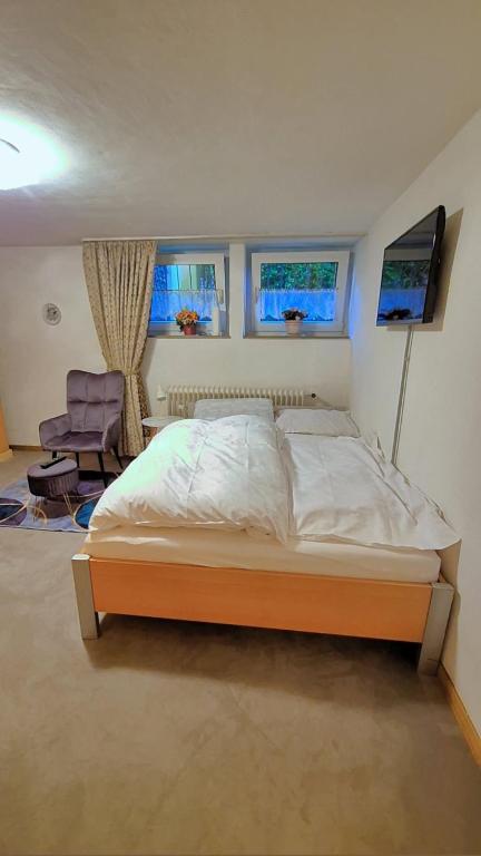 ein Schlafzimmer mit einem Bett, einem Stuhl und zwei Fenstern in der Unterkunft Einzelzimmer in Oberhausen Alstaden für 3 Personen ohne Küche, Gefrierschrank und Mikrowelle Vorhanden!! in Oberhausen