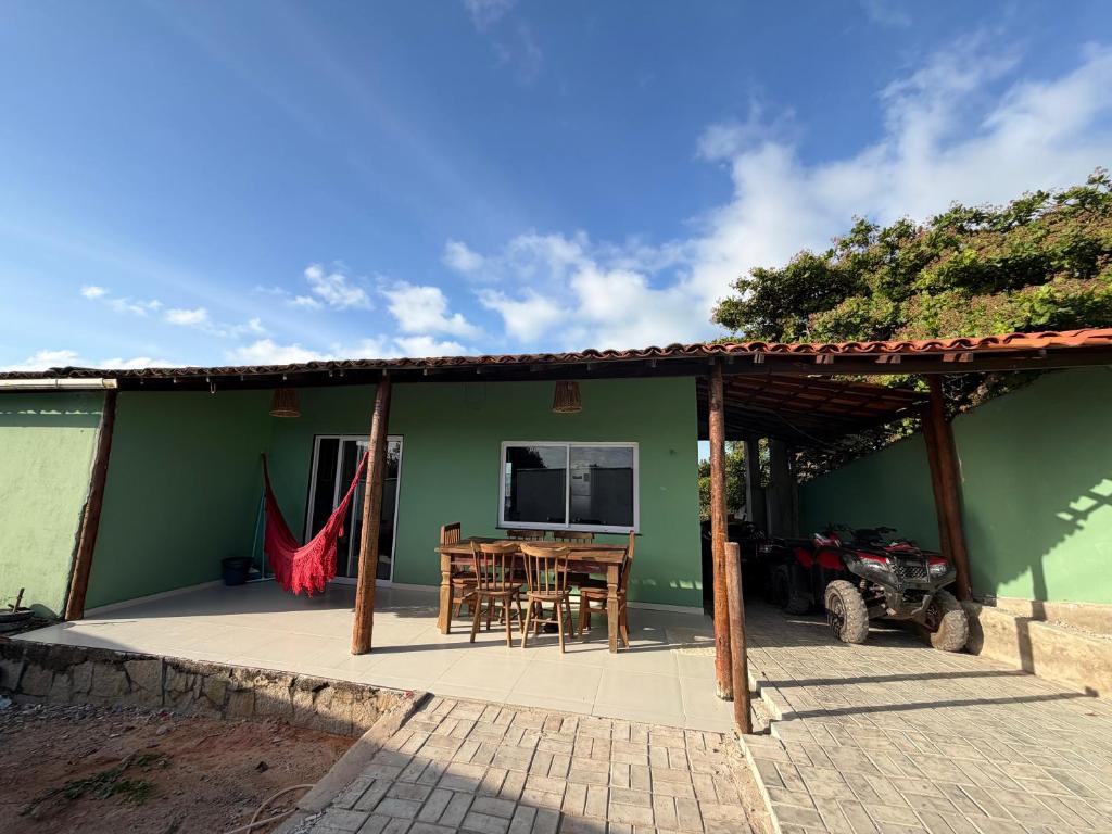 een groen huis met een tafel en een televisie bij Casa Flor do Deserto in Pipa