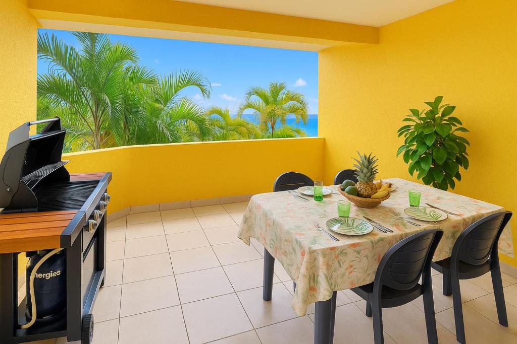 a dining room with a table and a yellow wall at Le Poinsettia d'Or T3 élégant proche Maïdo & piscine in Le Bois de Nèfles