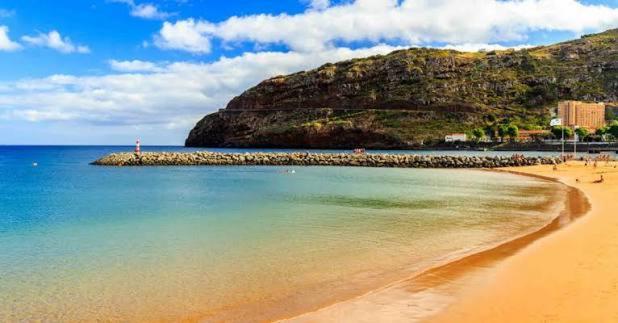 a beach with a bunch of people on the water at Machico Bay in Machico