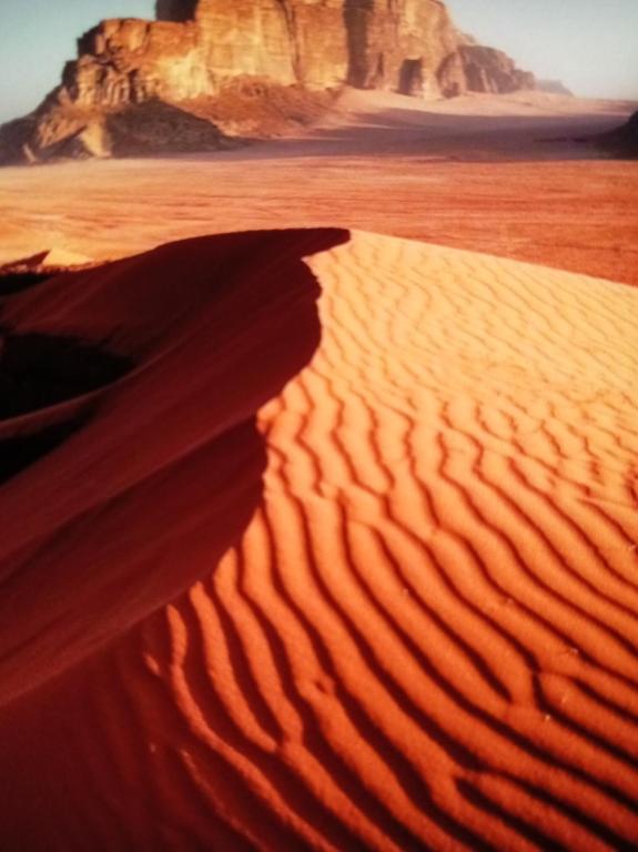 ワディ・ラムにあるRum Adventures Hostelの背景に山がある砂漠の砂丘