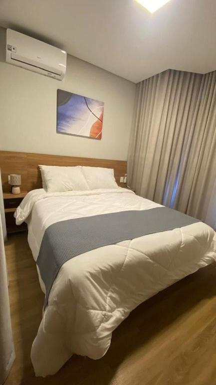 a bedroom with a large white bed and a fan at Flat 102 Conforto e Charme in Canela