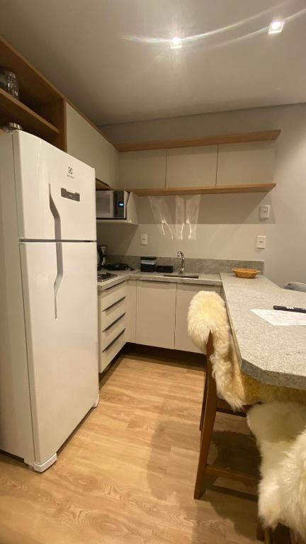 a kitchen with a white refrigerator and a table at Studio 211 Conforto e Charme in Canela